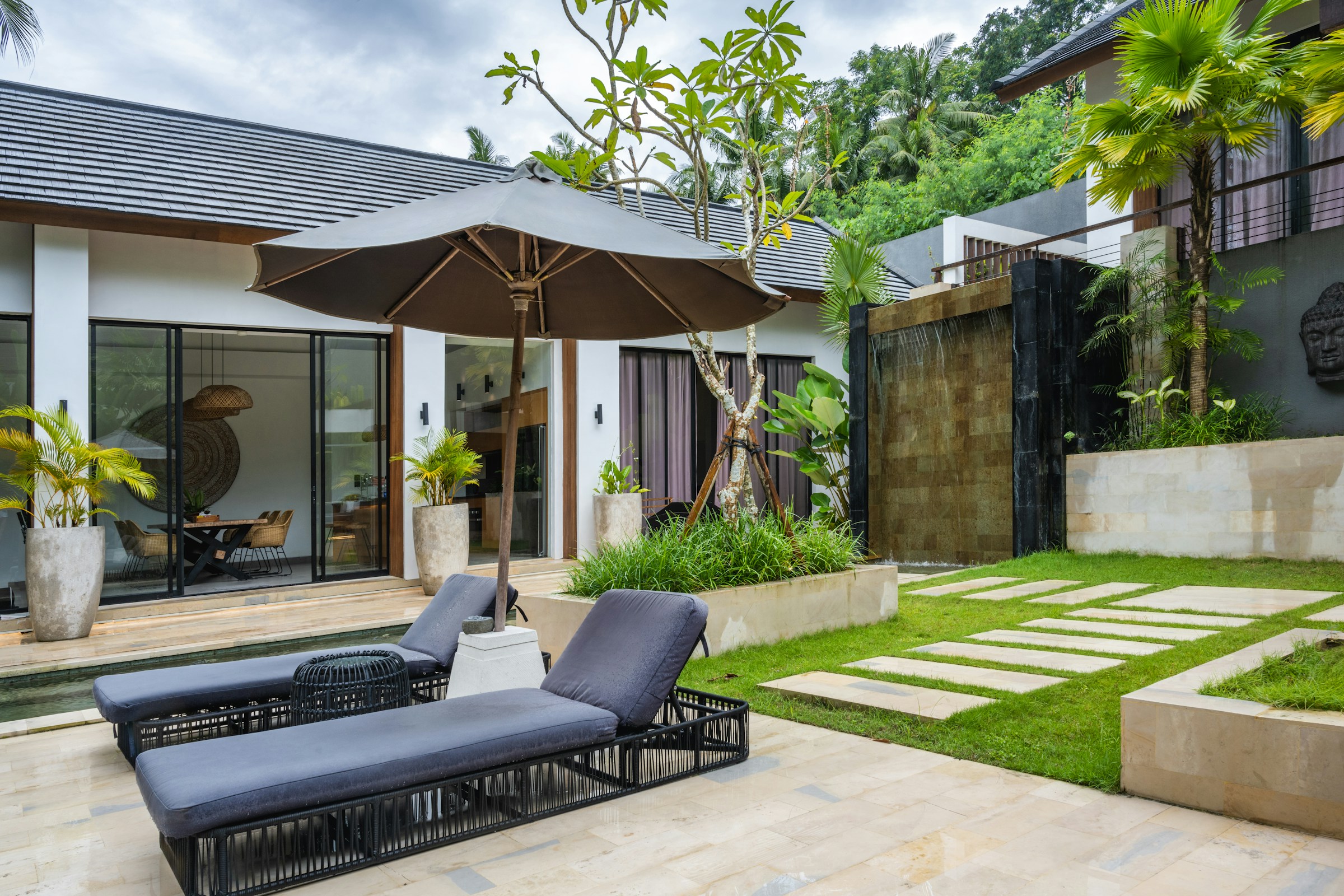 A peaceful green backyard with a patio surrounded by trees